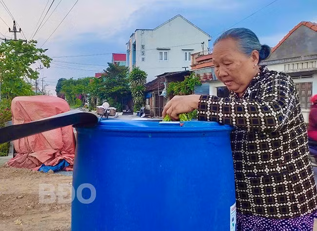 Bà Đỗ Thị Bích Hoa (thôn Định Thiện Đông, xã Phước Quang, huyện Tuy Phước) ủ phân bằng rác thải hữu cơ tại thùng ủ do Hội LHPN xã Phước Quang đặt. Ảnh: T.K