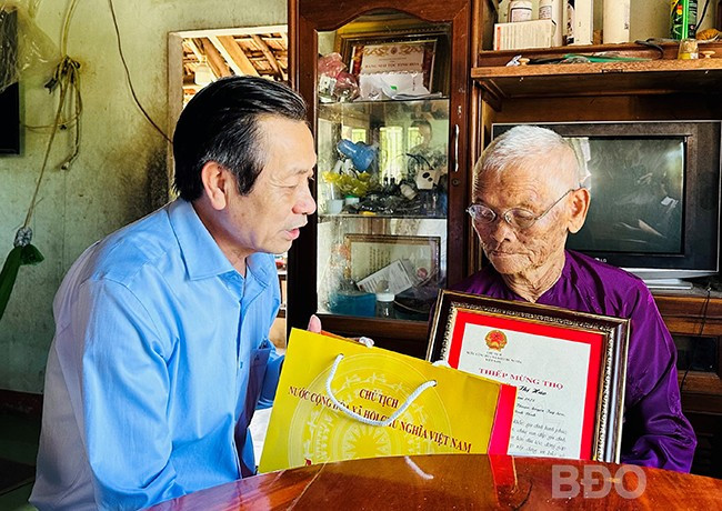 Phó Chủ tịch Thường trực HĐND tỉnh Đoàn Văn Phi tặng quà, thiếp mừng thọ của Chủ tịch nước cho cụ Mai Thị Hảo. Ảnh: D.Đ