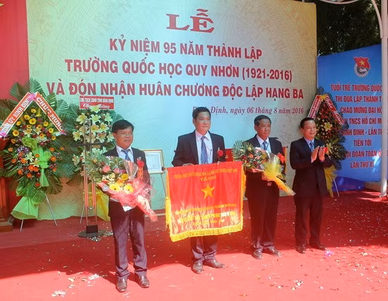 Phó Chủ tịch UBND tỉnh Nguyễn Tuấn Thanh (bìa phải) trao Cờ thi đua của Thủ tướng Chính phủ cho ban giám hiệu nhà trường.