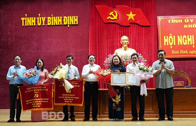 Bà Lưu Thị Kim Định, Phó Bí thư Chi bộ Chi nhánh Ngân hàng CSXH tỉnh (thứ hai từ trái sang) nhận cờ thi đua của Ban Thường vụ Tỉnh ủy về thành tích hoàn thành xuất sắc nhiệm vụ 5 năm liền (2020 - 2024). Ảnh: N.H Bà Lưu Thị Kim Định, Phó Bí thư Chi bộ Chi nhánh Ngân hàng CSXH tỉnh (thứ hai từ trái sang) nhận cờ thi đua của Ban Thường vụ Tỉnh ủy về thành tích hoàn thành xuất sắc nhiệm vụ 5 năm liền (2020 - 2024). Ảnh: N.H
