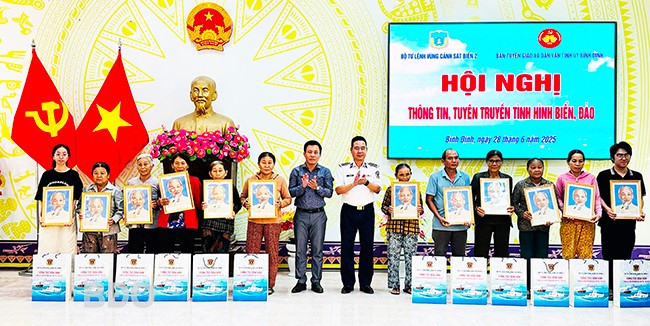 Lãnh đạo Bộ Tư lệnh Vùng Cảnh sát biển 2 và TX Hoài Nhơn tặng ảnh Bác Hồ và quà cho các hộ gia đình. Ảnh: D.Đ