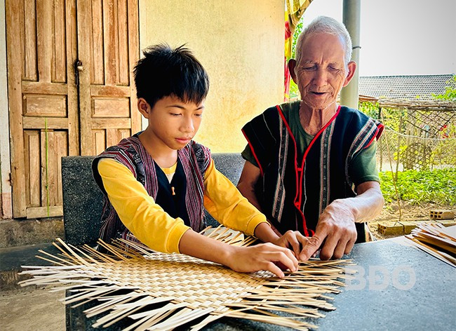 Ông Đinh Văn Tó “cầm tay, chỉ dẫn” cháu trai đan một cái đáp. Ảnh: T.C Ông Đinh Văn Tó “cầm tay, chỉ dẫn” cháu trai đan một cái đáp. Ảnh: T.C