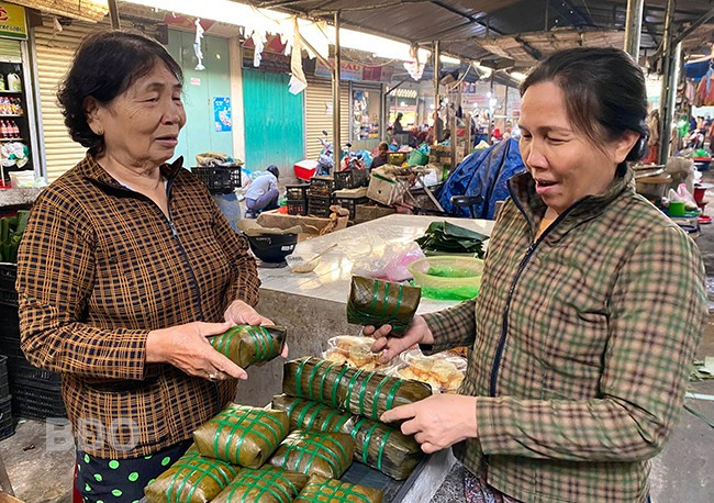 Ở tuổi 82, bà Trần Thị Thao (thị trấn Diêu Trì, huyện Tuy Phước, bên trái) vẫn gắn bó với nghề gói bánh chưng và sạp bánh chưng ở chợ Diêu Trì.