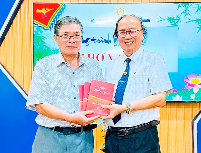 Nhà thơ Ngô Văn Cư (bên trái) tặng tác phẩm Cháy một mùa lặng lẽ cho bạn văn. Ảnh: NVCC