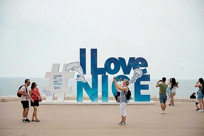 Khách du lịch chụp ảnh với thông điệp chào mừng hội nghị UNOC 3 tại Nice, Pháp. (Ảnh: AFP)