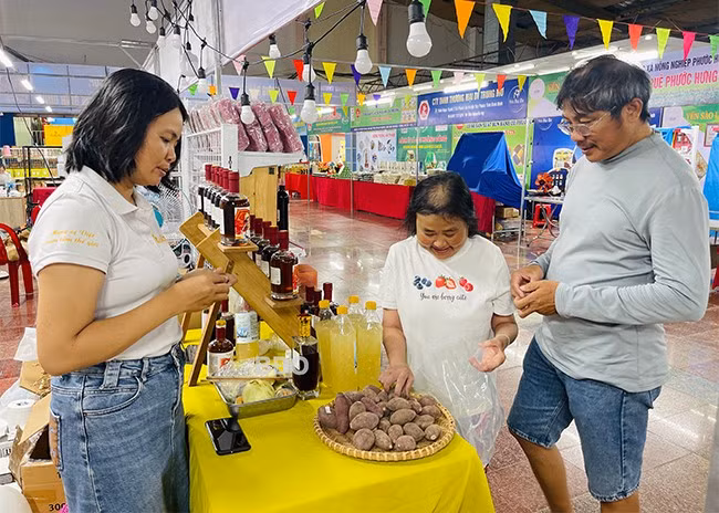 Khách đến mua bánh tráng khoai lang tím của Công ty TNHH Thực phẩm Trương Gia được thưởng thức miễn phí khoai lang tại gian hàng trưng bày. Ảnh: HẢI YẾN