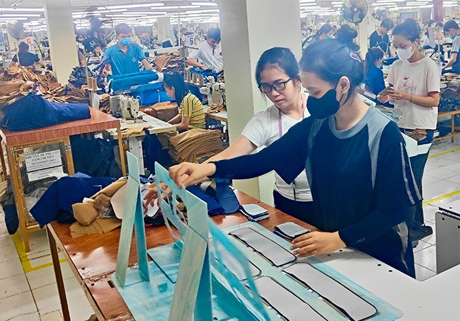 Chị Thúy (bên trái) hướng dẫn người lao động thực hiện kỹ thuật tại xưởng may. Ảnh: N.M