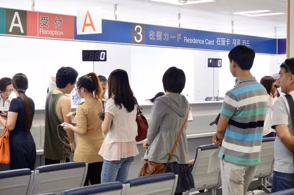 Người nước ngoài xếp hàng chờ nhận thẻ định cư tại một cơ quan nhập cư ở Osaka. Ảnh: Kyodo. Người nước ngoài xếp hàng chờ nhận thẻ định cư tại một cơ quan nhập cư ở Osaka. Ảnh: Kyodo.