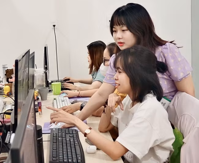 Chị Lan (đứng) hướng dẫn đồng nghiệp các thao tác sử dụng công cụ AI. Ảnh: D.L