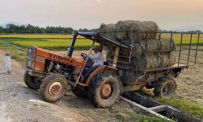 Xe máy cày gắn rơ moóc băng qua mương thủy lợi để leo lên đường giao thông ở thôn Tân Kiều (xã Nhơn Mỹ, TX An Nhơn). Ảnh: N.C