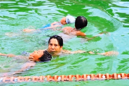 Thực hành cách bơi dìu người bị đuối vào bờ tại Lớp bồi dưỡng kiến thức kỹ thuật bơi phổ thông và bơi cứu đuối năm 2016. Ảnh: LÊ CƯỜNG