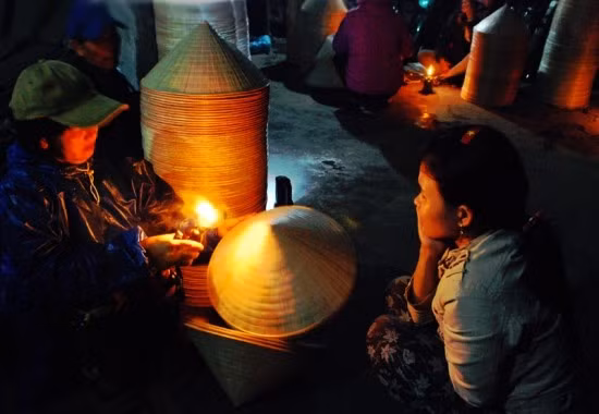 Bà Bùi Thị Lệ dùng đèn dầu để kiểm tra chất lượng của nón. Bà Bùi Thị Lệ dùng đèn dầu để kiểm tra chất lượng của nón.