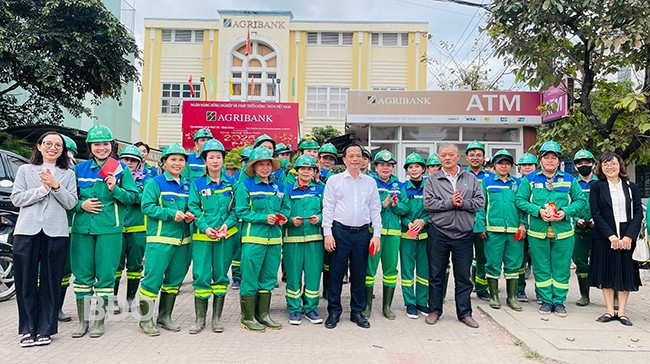 Phó Chủ tịch Thường trực UBND tỉnh Nguyễn Tuấn Thanh (thứ 7 từ trái sang hàng trên cùng) tặng quà cho công nhân đang làm việc tại đường Hùng Vương (TP Quy Nhơn). Ảnh: HẢI YẾN