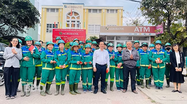 Phó Chủ tịch Thường trực UBND tỉnh Nguyễn Tuấn Thanh (thứ 7 từ trái sang hàng trên cùng) tặng quà cho công nhân đang làm việc tại đường Hùng Vương (TP Quy Nhơn). Ảnh: HẢI YẾN