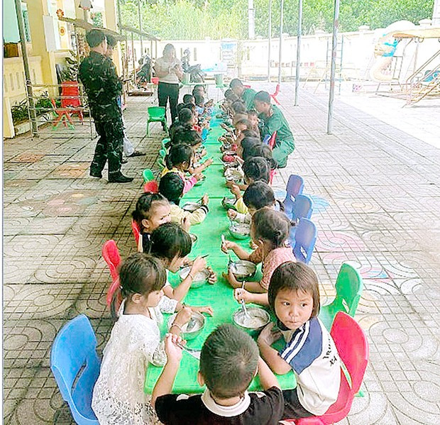 Cán bộ, chiến sĩ Ban CHQS huyện Sơn Tây (tỉnh Quảng Ngãi) mang cháo đến trường cho các cháu học sinh.