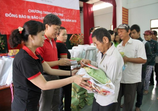 Ông Trần Đình Quân- Phó Tổng giám đốc điều hành Công ty Dai-ichi Life Việt Nam (áo đỏ) tặng quà cho các hộ gia đình ở phường Nhơn Phú.