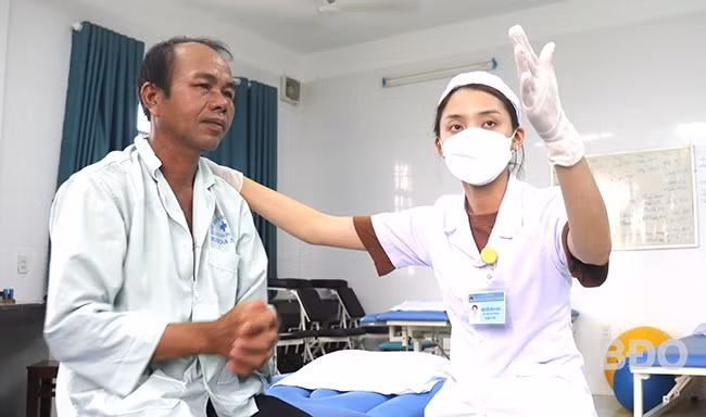 Bệnh nhân Lê Luôn cần mẫn từng chút tập phản xạ và các vận động tay, chân theo hướng dẫn của kỹ thuật viên Nguyễn Bích Hậu. Ảnh: M.H