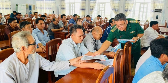 Cán bộ đồn Biên phòng Mỹ An cấp phát tờ rơi tuyên truyền cho ngư dân.