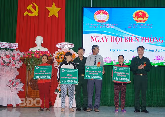 Đại diện Bộ Chỉ huy BĐBP tỉnh, Đồn Biên phòng Nhơn Lý trao sinh kế và kinh phí hỗ trợ xóa nhà tạm cho các hộ dân ở huyện Tuy Phước. Ảnh: CÔNG CƯỜNG