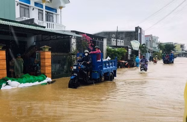 Lực lượng chức năng huyện Tuy Phước, tỉnh Bình Định, vận chuyển cát giúp người dân đắp bờ nước lũ tràn vào nhà. (Ảnh: TTXVN phát)