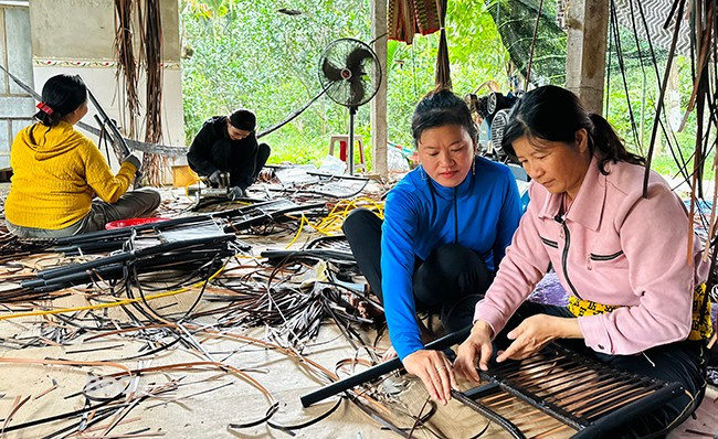 Chị Trương Thị Kim Hường (trái) hướng dẫn công nhân đan nhựa giả mây các chi tiết của sản phẩm. Ảnh: T.C