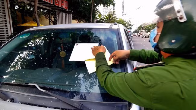 Lực lượng CSGT - Trật tự - Phản ứng nhanh (CA TP Quy Nhơn) dán biên bản lên kính ô tô vi phạm đỗ xe ngày chẵn, lẻ. Ảnh: M.N