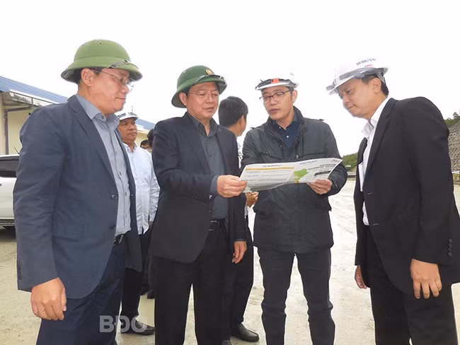 Đồng chí Hồ Quốc Dũng và Phạm Anh Tuấn (thứ 3 và 4 từ phải qua) nghe đại diện Ban Quản lý dự án 2 và nhà thầu thi công báo cáo tiến độ cao tốc Quảng Ngãi - Hoài Nhơn đoạn qua địa phận tỉnh Bình Định. Ảnh: V.L