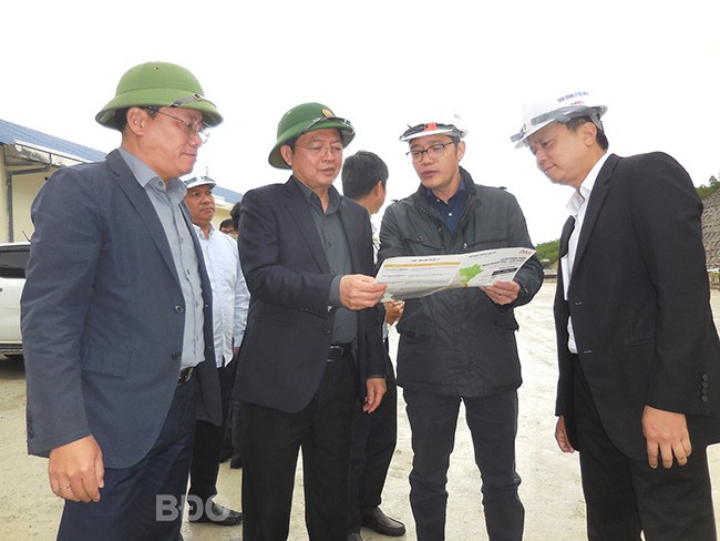 Đồng chí Hồ Quốc Dũng và Phạm Anh Tuấn (thứ 3 và 4 từ phải qua) nghe đại diện Ban Quản lý dự án 2 và nhà thầu thi công báo cáo tiến độ cao tốc Quảng Ngãi - Hoài Nhơn đoạn qua địa phận tỉnh Bình Định. Ảnh: V.L