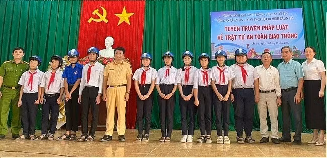 Lãnh đạo phòng CSGT CA tỉnh và đại diện chính quyền địa phương tặng mũ bảo hiểm cho đoàn viên, học sinh. Ảnh: Minh Ngọc