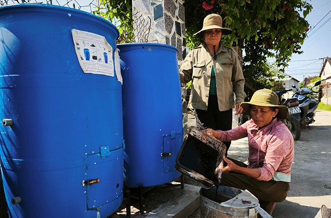 Bà Nguyễn Thị Tùng, thành viên Đội thu gom - ủ rác hữu cơ bằng chế phẩm sinh học tại Thuận Nghĩa, lấy dịch phân HCVS từ thùng ủ rác thải hữu cơ. Ảnh: ĐINH NGỌC