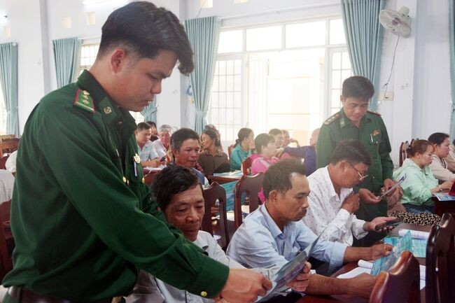 Cán bộ Đồn Biên phòng Mỹ An cấp phát tài liệu tuyên truyền pháp luật cho ngư dân. Ảnh: Công Cường.