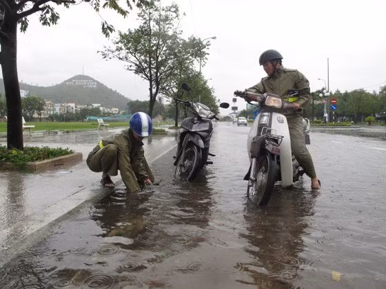 Công nhân Công ty CP Môi trường đô thị Quy Nhơn, khơi thông các hố ga để hạn chế ngập úng do mưa lớn. Ảnh: N.PHÚC