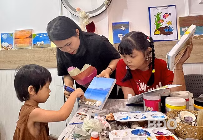 Trẻ hào hứng, tự tay làm tranh gắn vỏ ốc tại buổi sinh hoạt của CLB Handmade Quy Nhơn. Ảnh: D.L