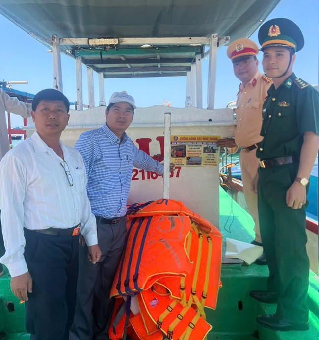 Tổ công tác dán áp-phích tuyên truyền tuân thủ Luật Giao thông đường thủy trên tàu của ngư dân. Ảnh: Ban ATGT tỉnh