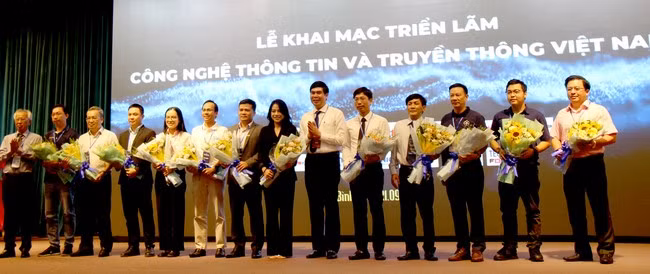 Phó Chủ tịch UBND tỉnh Bình Định Lâm Hải Giang (đứng thứ sáu, bên phải) tặng hoa cho đại diện DN CNTT tham gia Triển lãm. Ảnh: TRỌNG LỢI