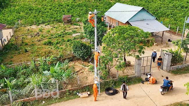 Công nhân Điện lực Phú Tài lắp đặt công tơ tại trụ điện ở làng. Ảnh: HẢI YẾN