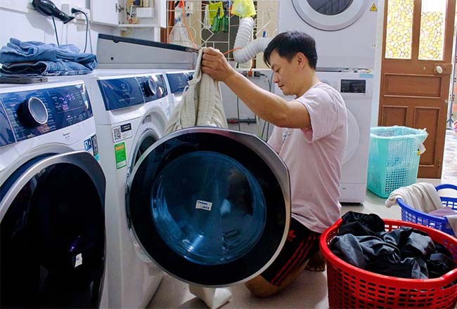 Anh Trần Thành Hảo đang phân loại trang phục để cho vào máy giặt. Ảnh: T.N