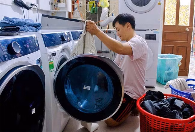 Anh Trần Thành Hảo đang phân loại trang phục để cho vào máy giặt. Ảnh: T.N