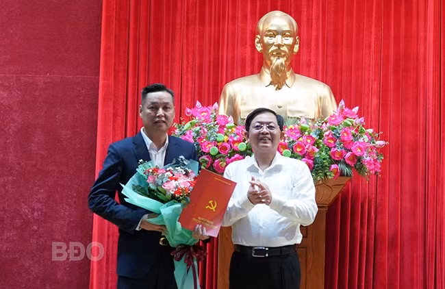 Đồng chí Hồ Quốc Dũng, Ủy viên Trung ương Đảng, Bí thư Tỉnh ủy, Chủ tịch HĐND tỉnh (bên phải) trao quyết định của Ban Bí thư, tặng hoa chúc mừng đồng chí Mai Anh Tài. Ảnh: N.H