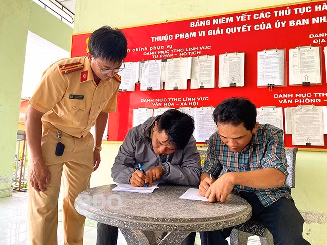 Anh Nguyễn Xuân Hòa (bìa phải) viết giấy cam kết không sử dụng xe độ chế tham gia giao thông. Ảnh: N.C