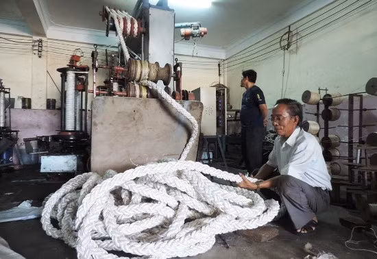 Ông Lê Văn Quyền (người ngồi) và chiếc máy đánh dây 8 tao đôi độc đáo do ông tự mày mò nghiên cứu chế tạo.