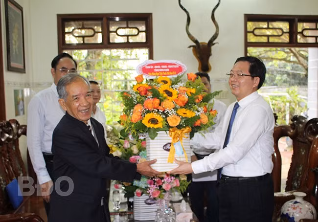 Bí thư Tỉnh ủy Hồ Quốc Dũng (bên phải) tặng lẵng hoa chúc mừng thầy thuốc Nhân dân Triệu Nguyên Trung. Ảnh: N. HÂN