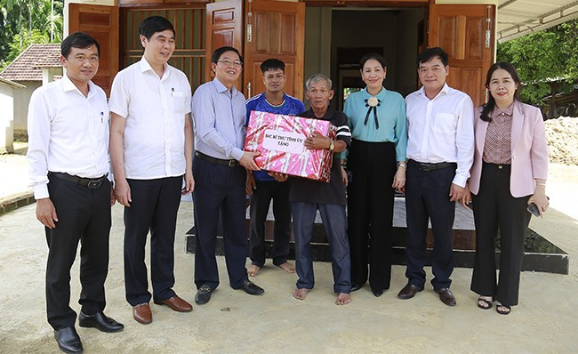 Bí thư Tỉnh ủy Hồ Quốc Dũng (thứ ba, từ trái qua) đến thăm và tặng quà gia đình ông Đinh Văn Túc (hộ nghèo) ở xã An Lão. Ảnh: HỒNG PHÚC