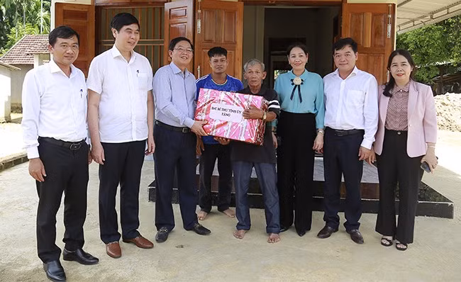 Bí thư Tỉnh ủy Hồ Quốc Dũng (thứ ba, từ trái qua) đến thăm và tặng quà gia đình ông Đinh Văn Túc (hộ nghèo) ở xã An Lão. Ảnh: HỒNG PHÚC