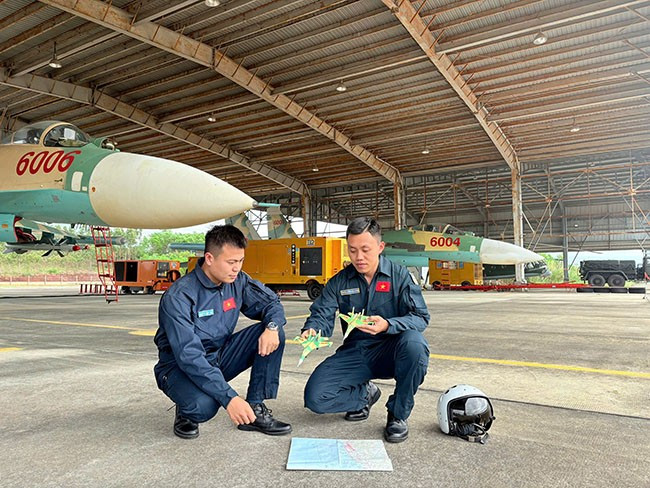 Đại úy Nguyễn Hoàng Hải Quang (bên phải) cùng đồng đội rút kinh nghiệm sau chuyến bay. Ảnh: N.K Đại úy Nguyễn Hoàng Hải Quang (bên phải) cùng đồng đội rút kinh nghiệm sau chuyến bay. Ảnh: N.K