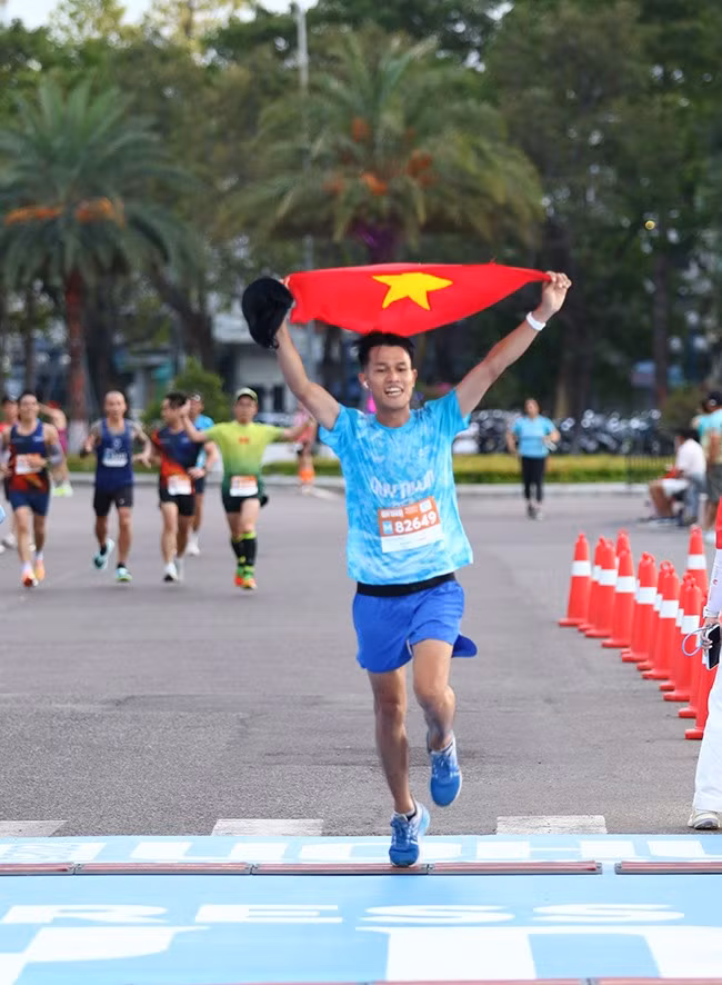 Một VĐV về đích đầy ấn tượng với lá quốc kỳ giơ cao.
