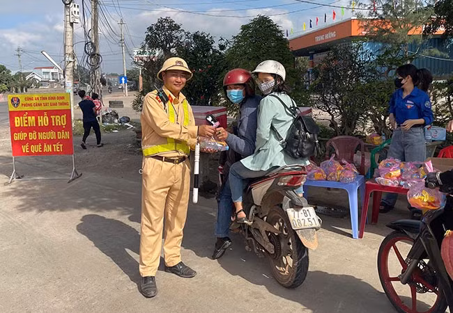 CSGT CA tỉnh Bình Định phát nước hỗ trợ người dân trên đường về quê đón Tết. Ảnh: THU HÀ CSGT CA tỉnh Bình Định phát nước hỗ trợ người dân trên đường về quê đón Tết. Ảnh: THU HÀ