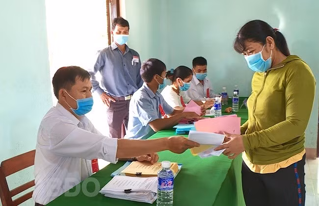Cử tri xã An Quang nhận phiếu bầu. ẢNH: HỮU BÁ