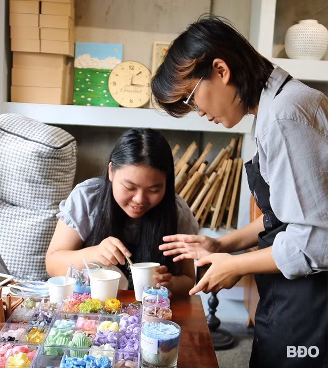 Chị Hồ Thị Phương Linh hướng dẫn một học sinh làm nến thơm tại Bà Ngoại Crochet. Ảnh: H.THU