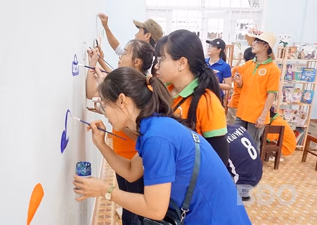 Vẽ tranh tường, trang trí góc thư viện là một trong những hoạt động cố định được các tình nguyện viên chăm chút. - Trong ảnh: Các tình nguyện viên trang trí điểm đọc tại Trường Tiểu học An Toàn (xã An Toàn, huyện An Lão). Ảnh: D.L